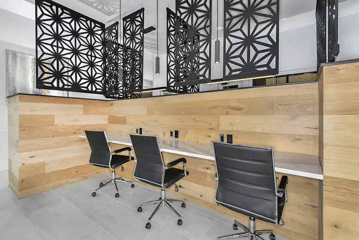 Modern workspace with sleek black chairs, geometric patterned dividers, and stylish wood paneling.