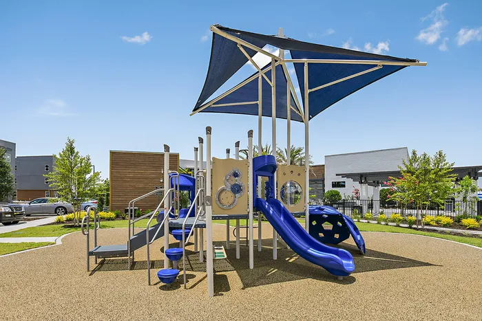 Modern playground with vibrant blue slides and innovative climbing structures, perfect for active play in a beautifully landscaped community setting.