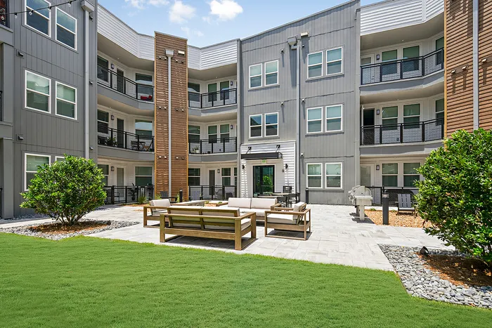 Modern apartment courtyard featuring cozy outdoor seating, lush greenery, and stylish architectural design.