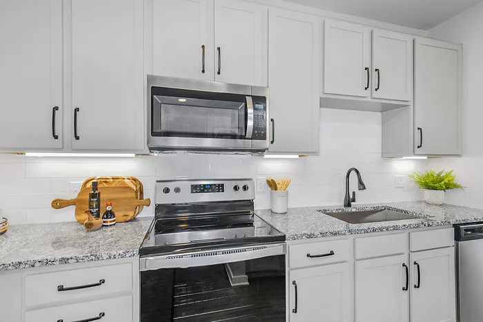 Contemporary kitchen with sleek granite countertops, modern stainless steel appliances, and stylish white cabinetry.