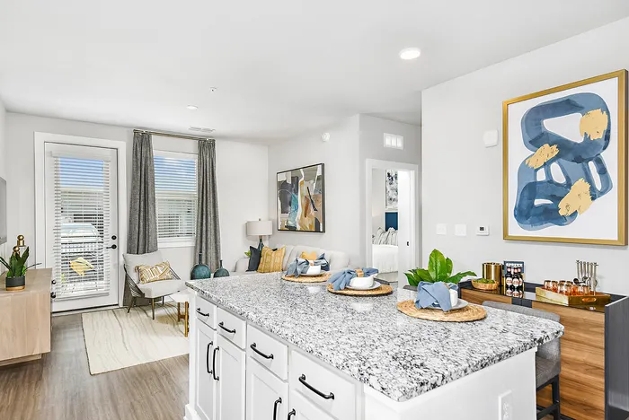 Bright and modern living space featuring a stylish kitchen island with granite countertop, elegant dining setup, and cozy seating area with chic decor.
