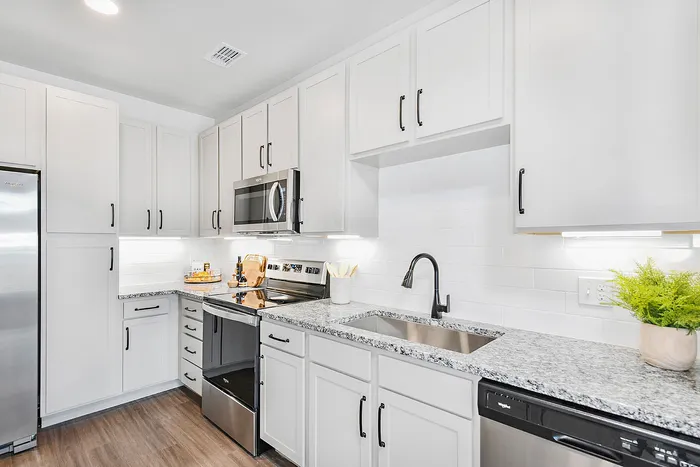Modern kitchen with sleek white cabinetry, stainless steel appliances, and elegant granite countertops, perfect for culinary creativity.