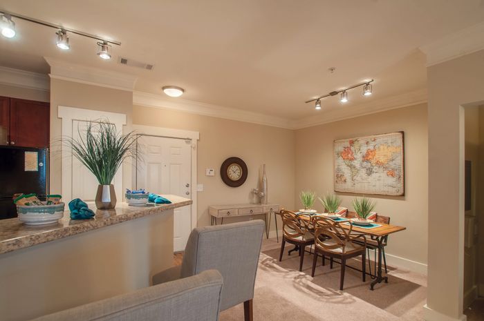 Inviting dining area with a world map art piece, elegant wooden table, and plush seating, adjacent to a stylish kitchen countertop with modern decor.