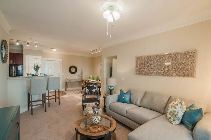 Inviting living room with elegant decor featuring a cozy sectional sofa, stylish bar stools, and vibrant artwork in a modern apartment.