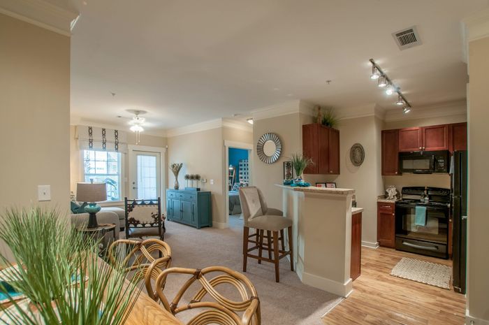 Inviting open-plan living space with modern kitchen, chic bar seating, and elegant dining area, bathed in natural light.