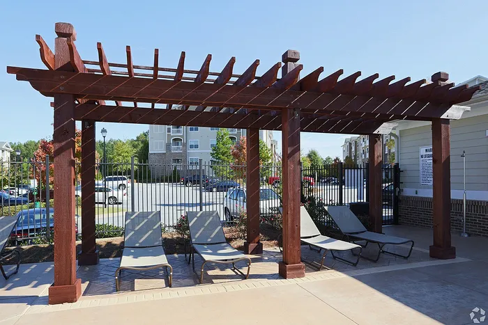 Inviting outdoor space with a stylish wooden pergola and comfortable loungers, perfect for relaxation and enjoying sunny days.