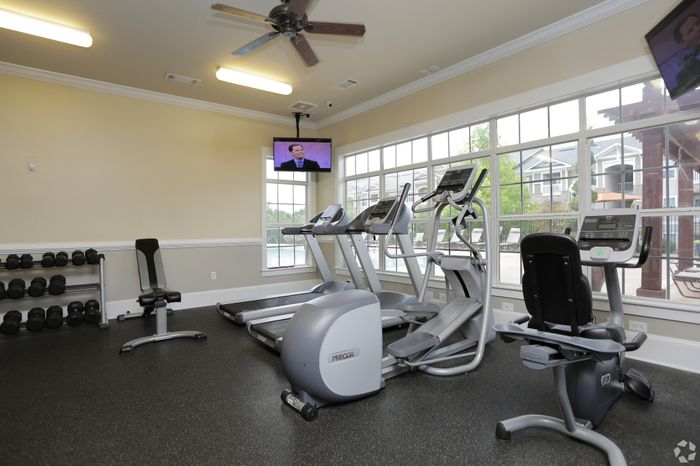 Modern fitness center with state-of-the-art cardio machines and panoramic windows overlooking a serene outdoor area.