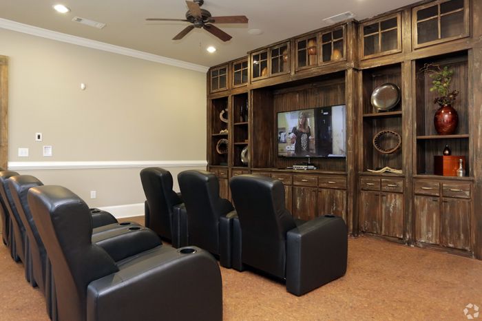 Elegant home theater with plush leather seating, rustic wooden cabinetry, and a large television for ultimate entertainment experience.