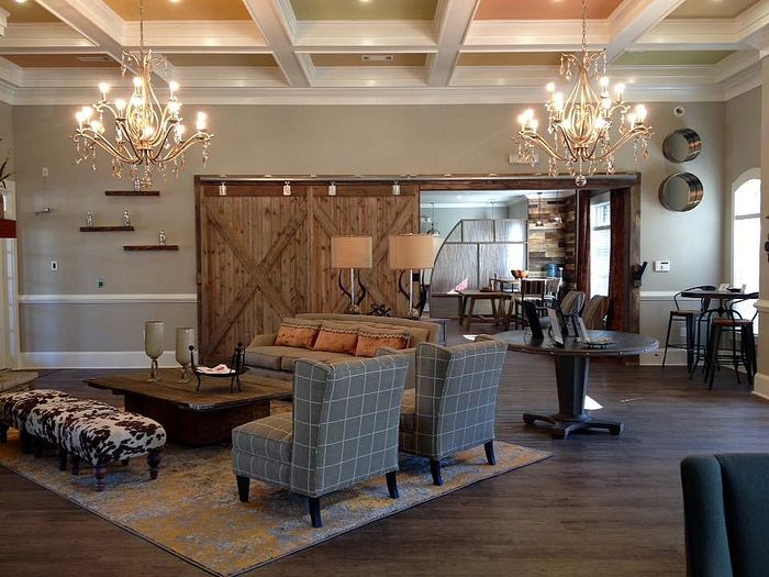 Luxurious living room with elegant chandeliers, rustic barn door, and plush seating, perfect for relaxation and entertainment.