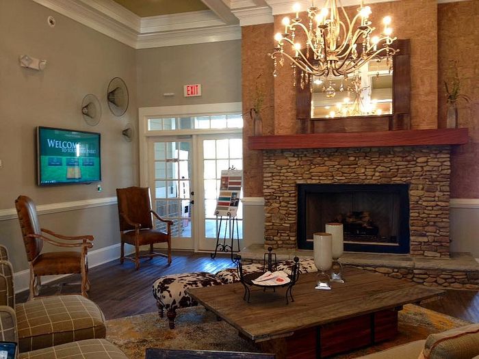 Inviting living area with a rustic stone fireplace, elegant chandelier, and comfortable seating, ideal for a cozy atmosphere.
