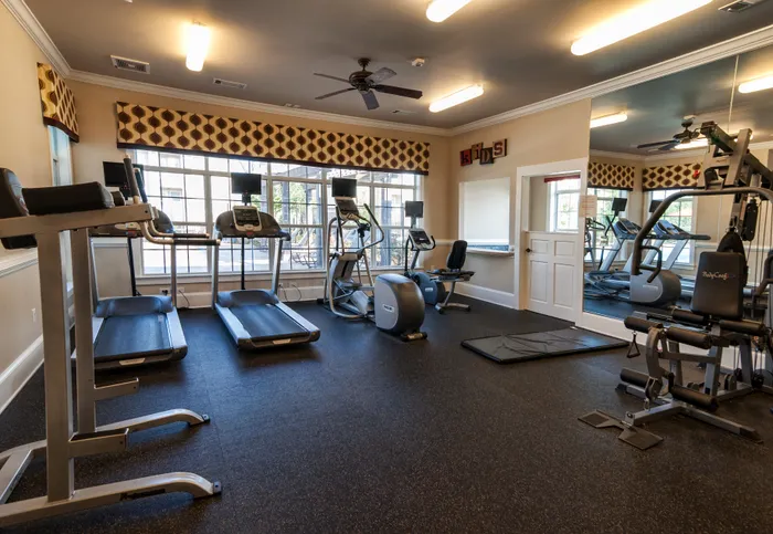 Modern fitness center featuring state-of-the-art treadmills, elliptical machines, and weight equipment in a bright, inviting setting.