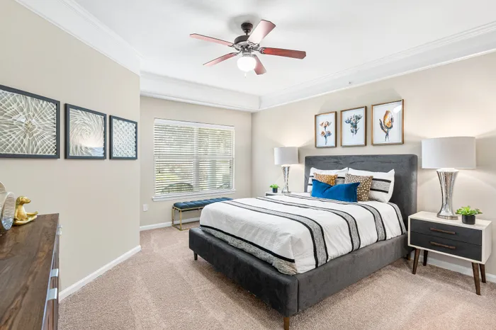 Modern bedroom with elegant decor, featuring a plush bed with stylish pillows, artistic wall hangings, and ambient lighting.
