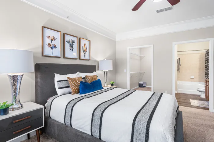 Elegant bedroom with plush gray bed, stylish artwork, modern lamps, and a spacious walk-in closet.