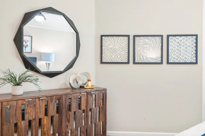 Elegant living space featuring a modern octagonal mirror, contemporary art pieces, and a stylish wooden cabinet.