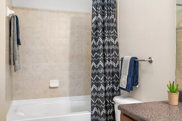 Modern bathroom with elegant patterned shower curtain, sleek tiled walls, and plush towels for a cozy touch.