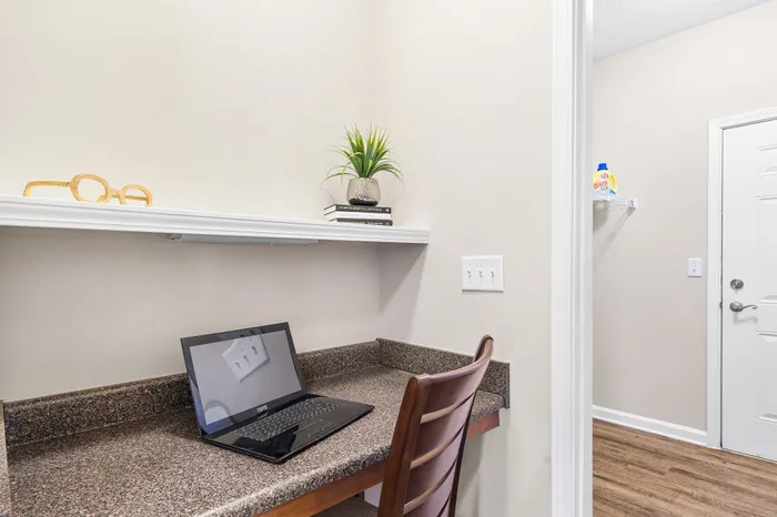 Charming nook with a built-in desk featuring a laptop and decor, ideal for a cozy workspace in an elegant apartment.