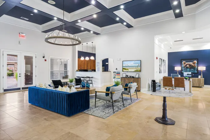 Elegant open-concept living space with stylish blue sofa, modern pendant lighting, and high ceilings, perfect for luxury living.