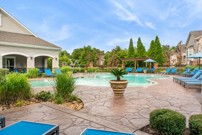 Luxurious outdoor pool area with elegant lounge chairs, lush greenery, and a peaceful arbor, perfect for relaxation on a sunny day.