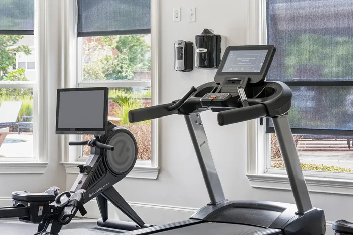 Modern home gym with state-of-the-art treadmill and stationary bike, offering a bright and airy workout space with large windows.