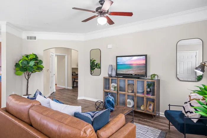 Charming living room with modern decor, featuring a cozy leather sofa, elegant wooden cabinetry, and a vibrant wall-mounted TV, perfect for relaxation.