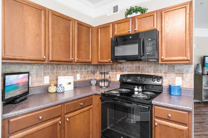 Charming kitchen with warm wooden cabinets, sleek black appliances, and elegant granite countertops for a cozy culinary experience.