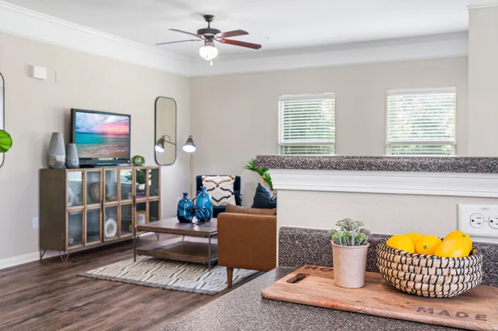 Chic open-concept living room with modern decor, featuring a cozy leather chair, stylish shelving, and vibrant accent pieces.