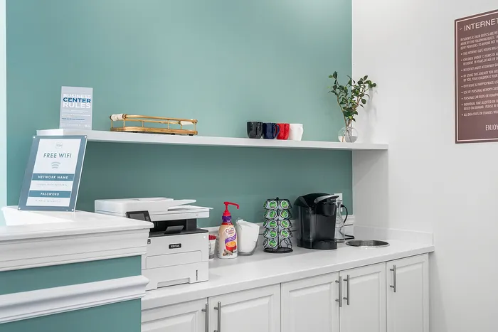 Modern apartment kitchenette with a coffee station, sleek printer, and free WiFi access, perfect for a productive and cozy atmosphere.