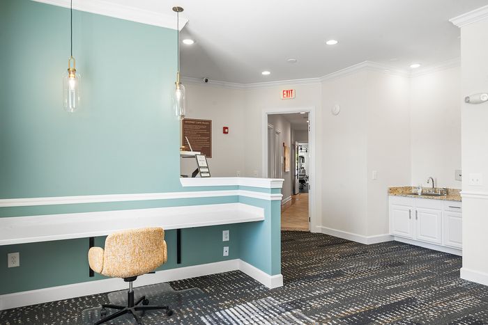 Chic office corner with teal accent wall, modern pendant lights, and sleek built-in desk, ideal for productivity and style.