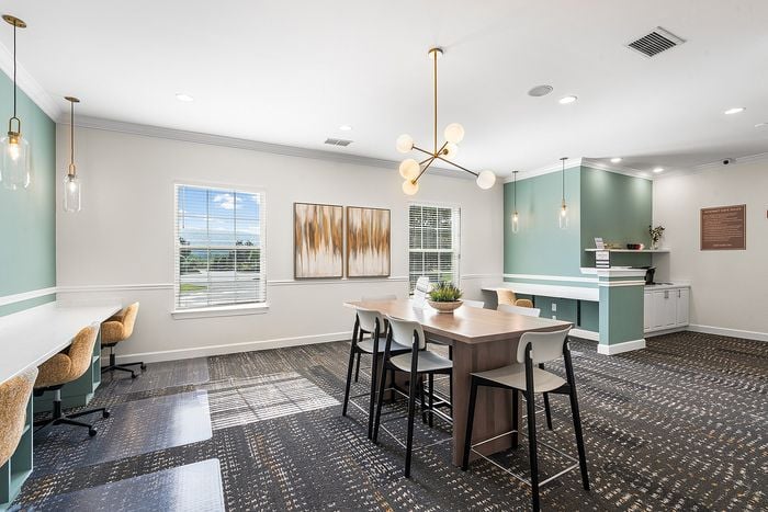 Bright and inviting communal area with modern design, featuring a large table, stylish pendant lighting, and cozy workspace seating.