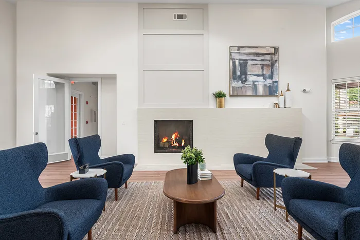 Elegant living room with modern blue armchairs, cozy fireplace, and stylish decor, perfect for relaxation.