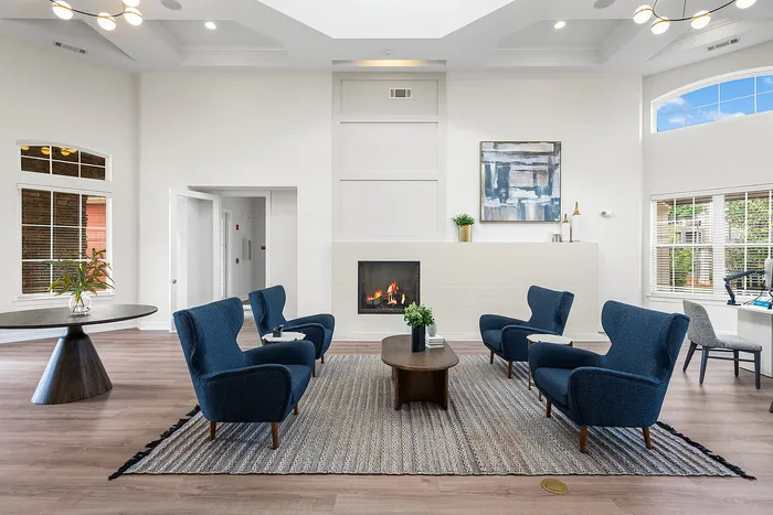 Elegant living room with stylish blue armchairs, cozy fireplace, and modern decor, perfect for relaxation and entertaining.