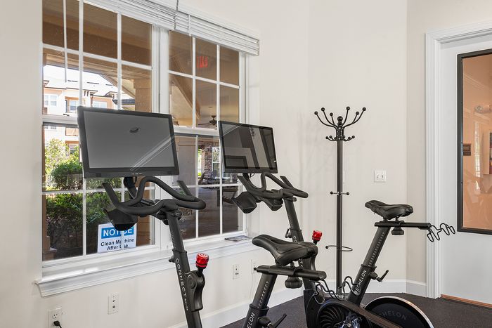 Bright, modern fitness room featuring two state-of-the-art exercise bikes with built-in screens, perfect for a dynamic workout experience.