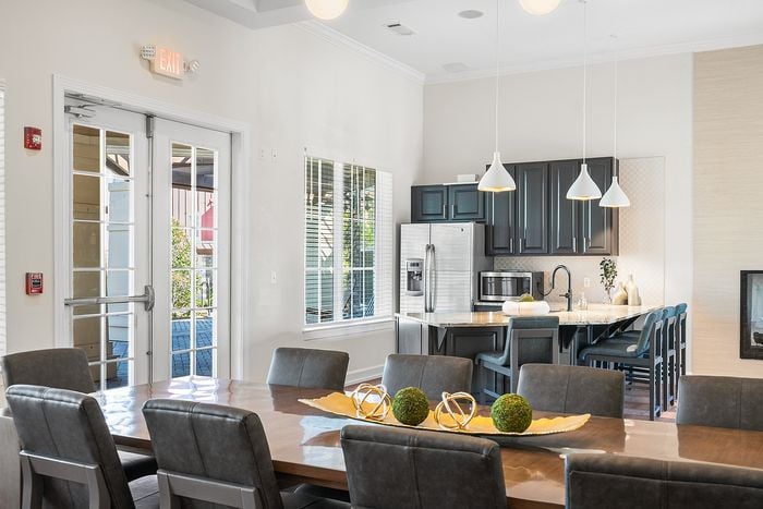 Modern, sunlit dining area with chic decor, adjacent to a sleek, open-concept kitchen featuring stainless steel appliances and elegant pendant lighting.