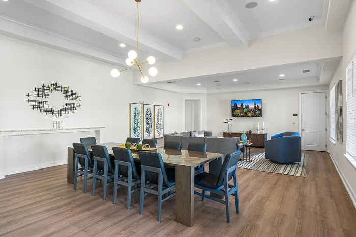 Elegant dining and living area featuring a stylish modern chandelier, spacious seating, and sleek decor with natural light.