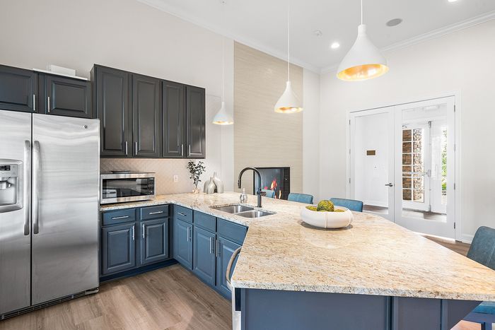 Elegant kitchen with stylish blue cabinetry, granite countertops, stainless steel appliances, and modern pendant lighting.