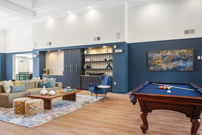 Elegant community room with modern decor featuring a cozy seating area, a chic pool table, and stylish wall art.