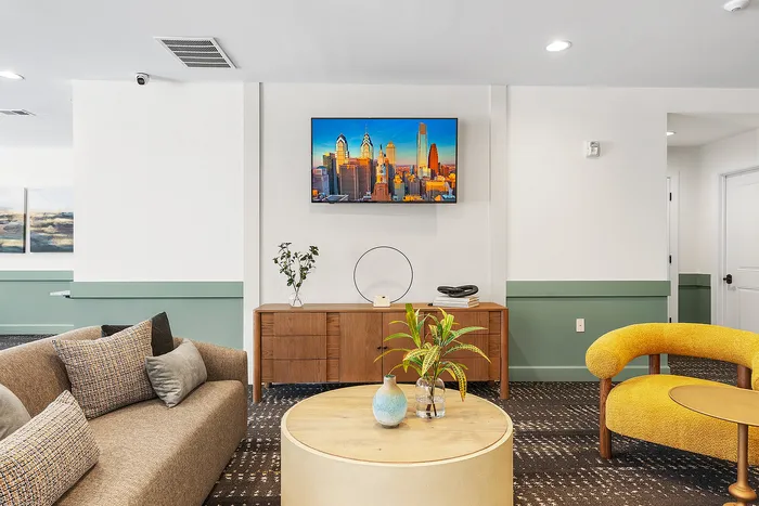 Modern living room with chic decor, featuring a cozy sofa, vibrant yellow armchair, and a sleek wooden console beneath a wall-mounted TV.