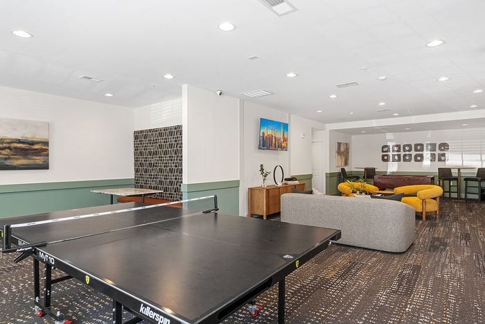 Modern recreation room with stylish lounge area, vibrant decor, and a ping pong table, perfect for relaxation and entertainment.