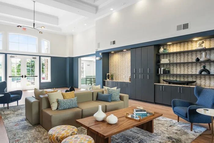 Elegant and spacious lounge with modern decor, featuring a cozy seating area, stylish wooden coffee table, and built-in shelving against a patterned accent wall.