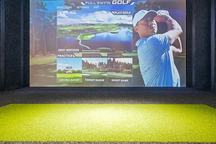 Immersive indoor golf simulator with vibrant Full Swing Golf interface, offering driving range, target range, and short game options.