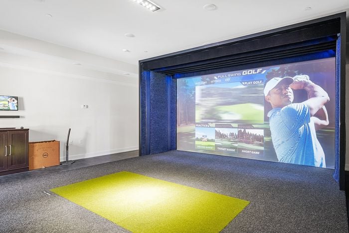 Luxury home golf simulator room with a state-of-the-art electronic screen and sleek modern design.