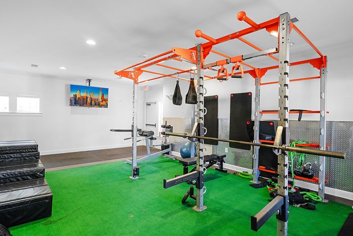 Modern gym facility with vibrant green flooring, featuring state-of-the-art fitness equipment and ample natural light.