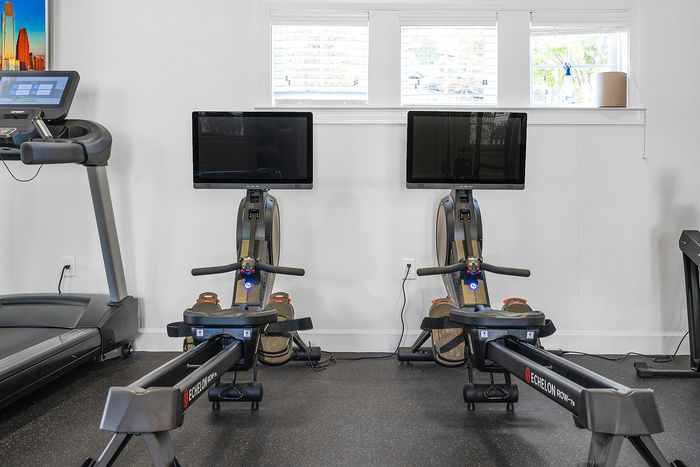 Modern fitness room featuring state-of-the-art treadmills and rowing machines, highlighting a bright and inviting atmosphere.