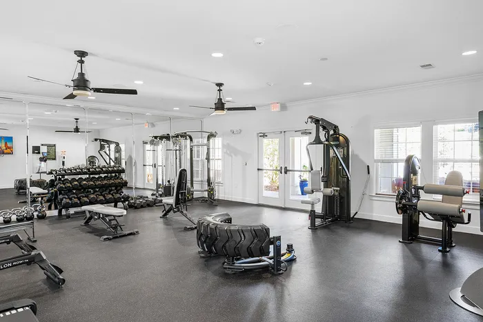 Modern apartment fitness center with state-of-the-art equipment, free weights, and spacious workout area.