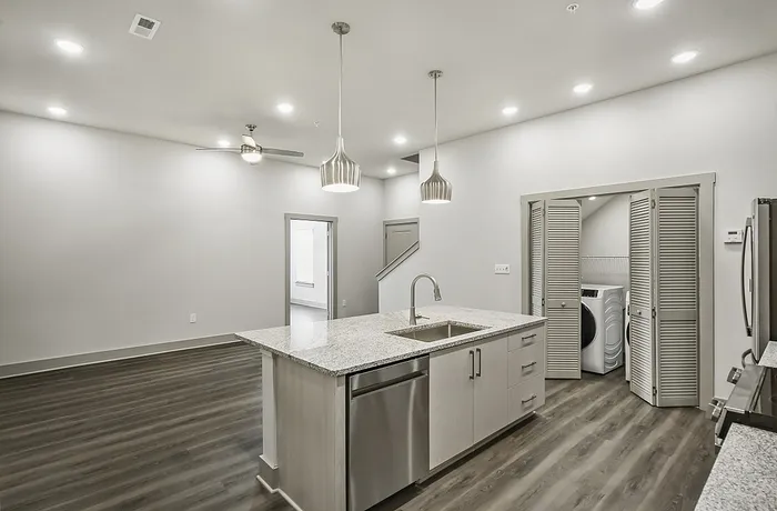 Sleek modern kitchen with granite countertops, pendant lighting, and integrated laundry area for ultimate convenience.