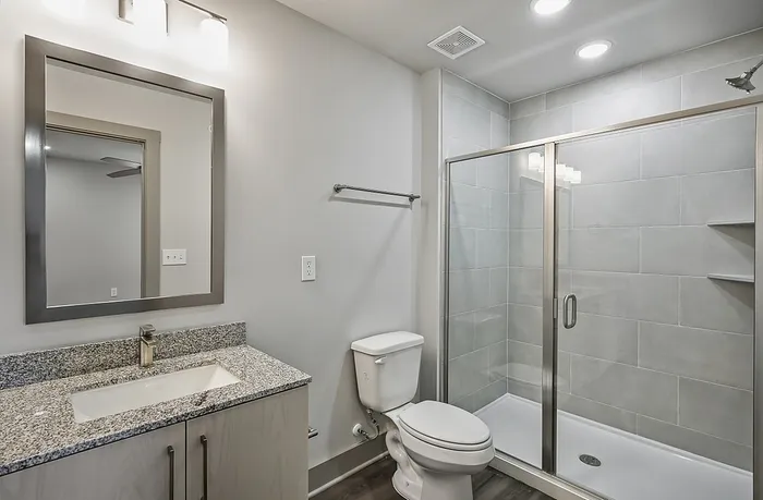 Modern bathroom design featuring sleek glass shower, elegant granite countertop, and contemporary fixtures, offering a luxurious experience.