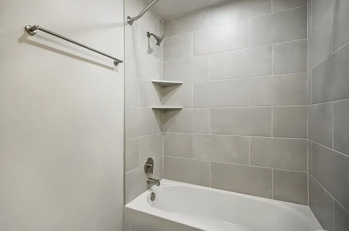 Modern bathroom showcasing a sleek bathtub with elegant tiled walls and chrome fixtures.