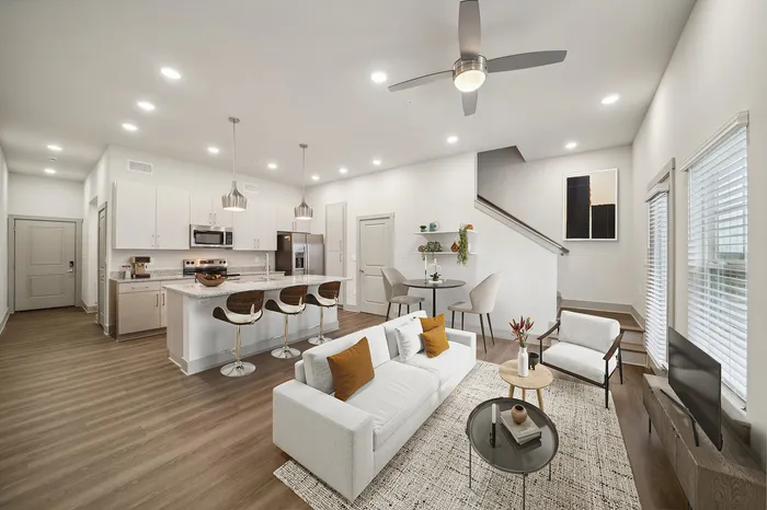 Modern open-concept living room and kitchen featuring sleek cabinetry, stylish island seating, and contemporary lighting, creating an inviting atmosphere.