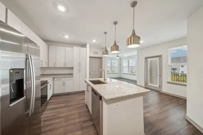 Elegant open kitchen with sleek stainless steel appliances, chic pendant lighting, and large windows offering natural light and outdoor views.