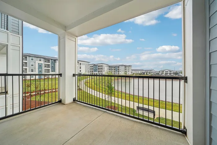 Inviting balcony view of a serene lake with modern apartments and a lush landscape, perfect for relaxation.